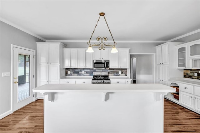 kitchen with decorative light fixtures, a kitchen bar, white cabinetry, and stainless steel appliances