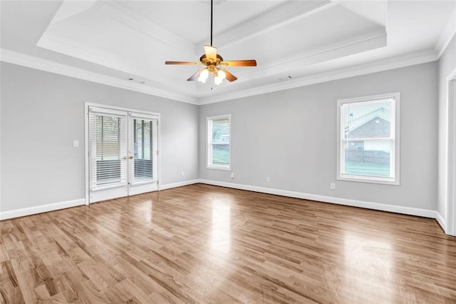 unfurnished room with light hardwood / wood-style floors, a tray ceiling, ornamental molding, and ceiling fan