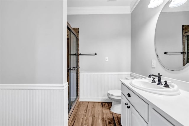 bathroom with toilet, vanity, crown molding, and an enclosed shower