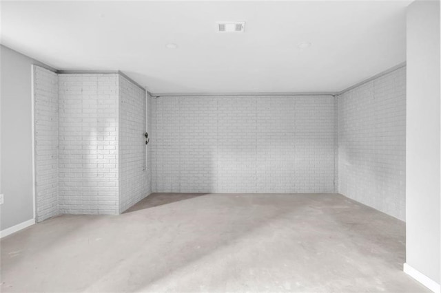 unfurnished room featuring brick wall