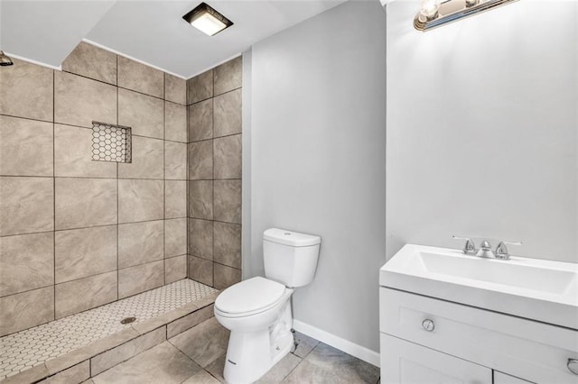 bathroom featuring vanity, toilet, tile patterned floors, and a tile shower