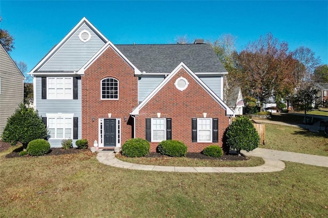 colonial house with a shingled roof, brick siding, and a front lawn