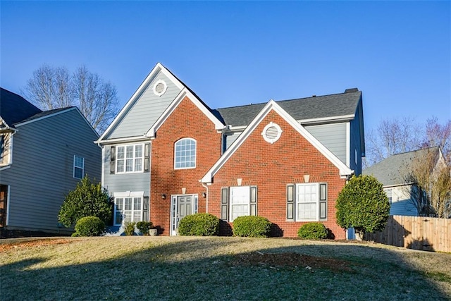 view of front of house with brick siding, fence, and a front lawn