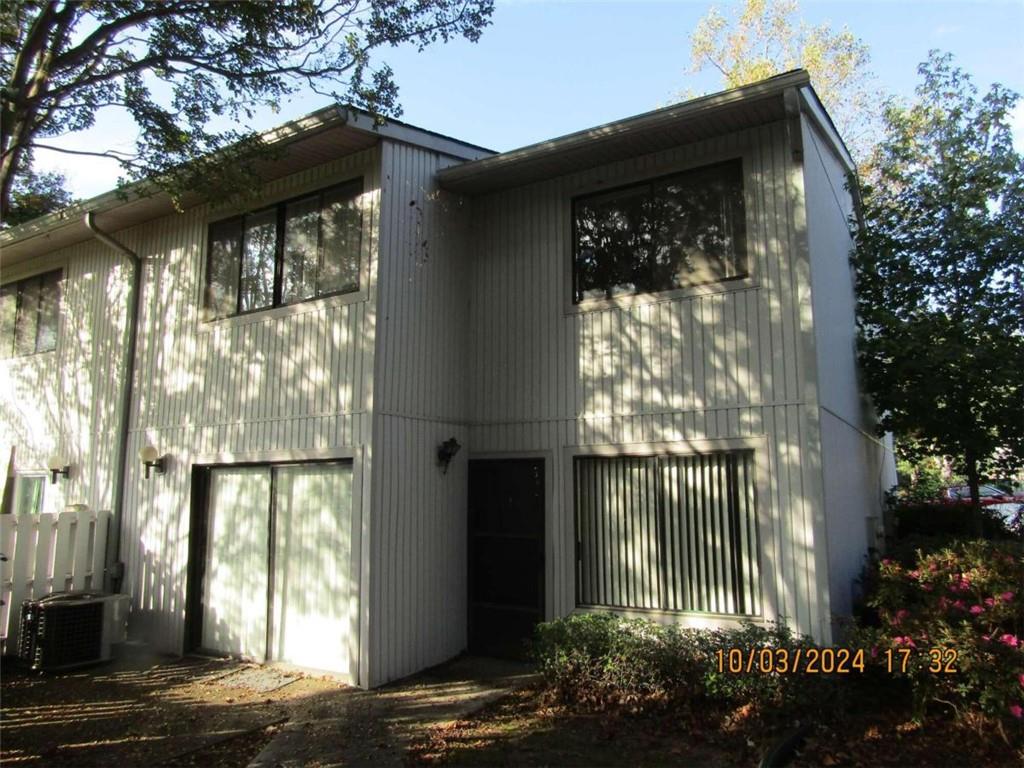 back of house with central AC unit and a garage