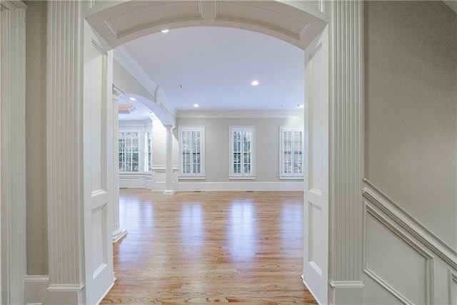 hall featuring decorative columns, ornamental molding, and light hardwood / wood-style flooring