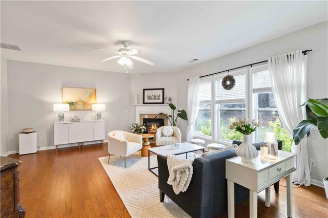 2319 White Alder Dr, Buford, GA 30519 - living area with wood finished floors, a glass covered fireplace, a ceiling fan, and visible vents