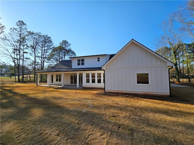 back of property featuring covered porch, a lawn, and board and batten siding