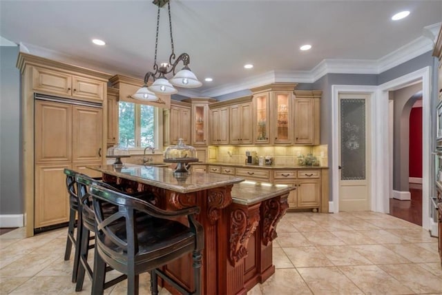 kitchen featuring pendant lighting, a kitchen island, light stone countertops, ornamental molding, and an inviting chandelier