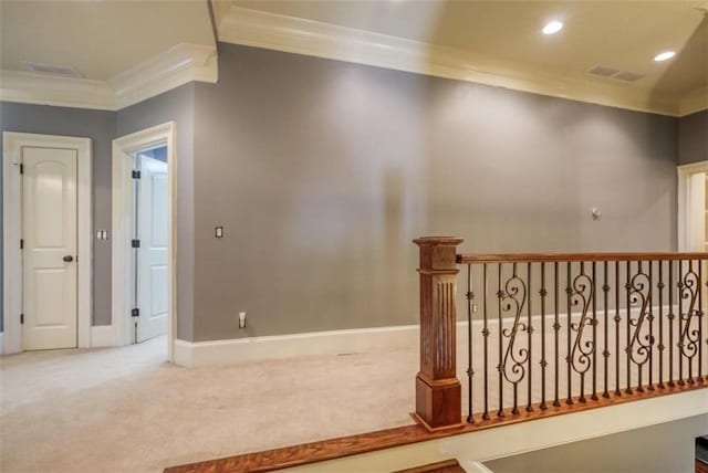 hall with ornamental molding and light colored carpet