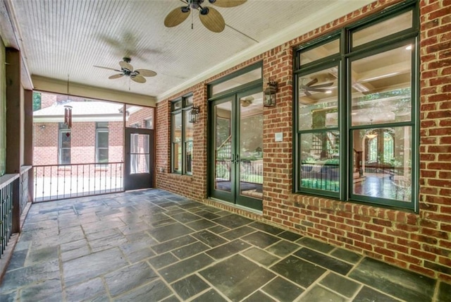 unfurnished sunroom featuring ceiling fan and plenty of natural light