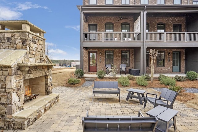 rear view of house with an outdoor stone fireplace and a patio area