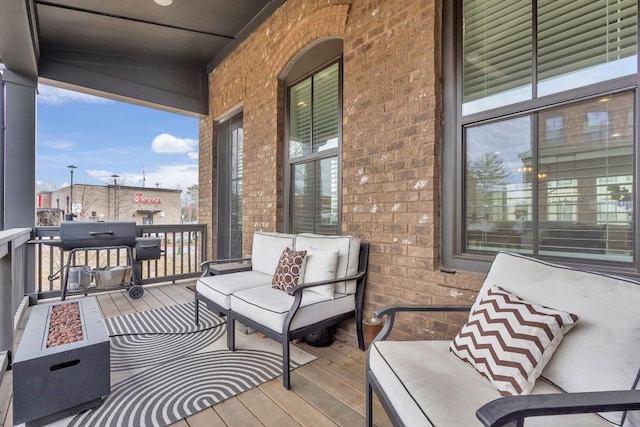 wooden terrace with an outdoor living space with a fire pit and grilling area