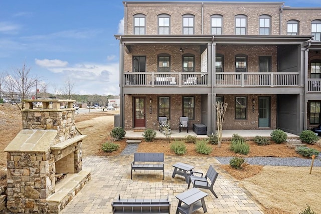 back of property featuring a patio and an outdoor stone fireplace