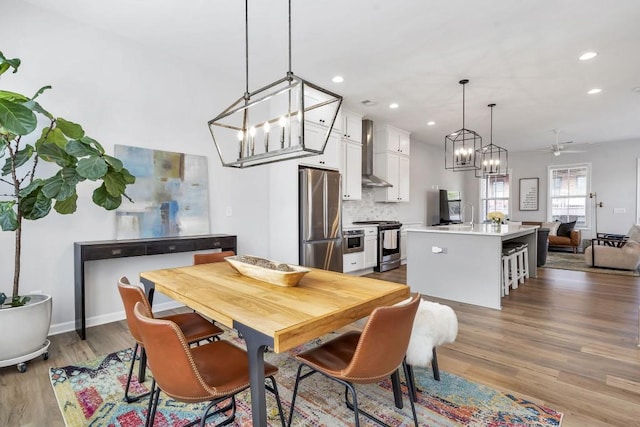 dining space featuring ceiling fan with notable chandelier and light wood-type flooring