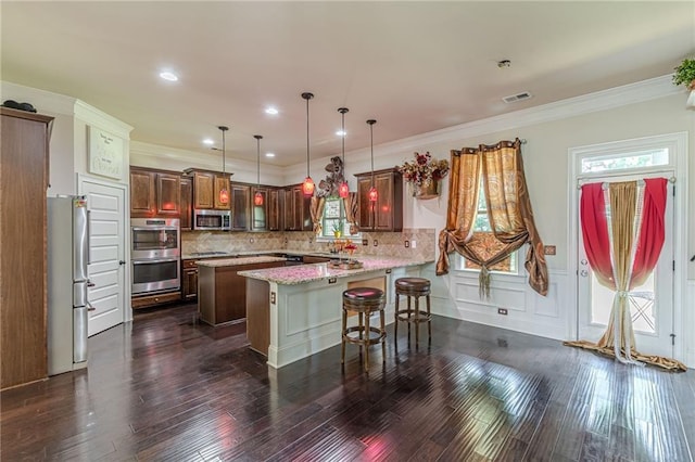 1405 Rainey Way, Hampton, GA 30228 - kitchen featuring appliances with stainless steel finishes, a breakfast bar area, a peninsula, dark wood-style flooring, and ornamental molding