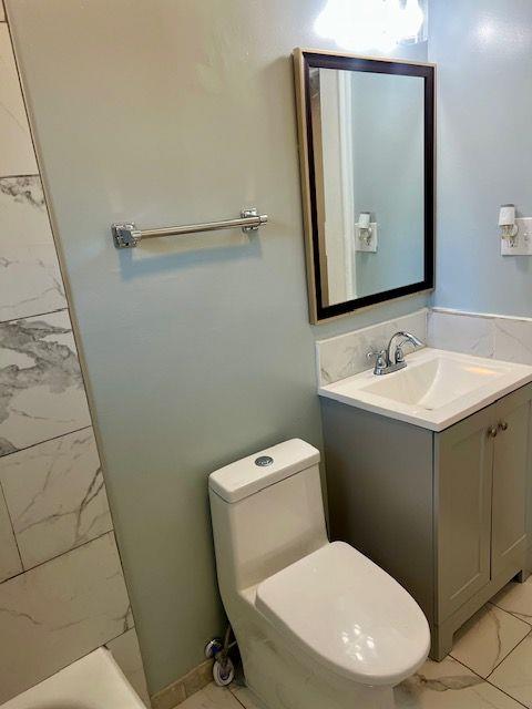 bathroom with vanity, a bath, and toilet