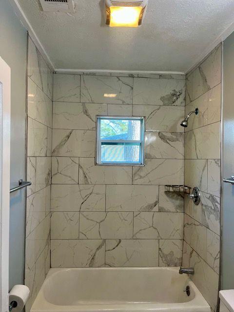 bathroom with tiled shower / bath combo and toilet