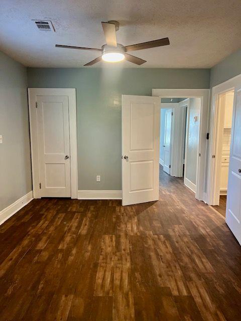 unfurnished bedroom with ceiling fan, dark hardwood / wood-style floors, and a textured ceiling