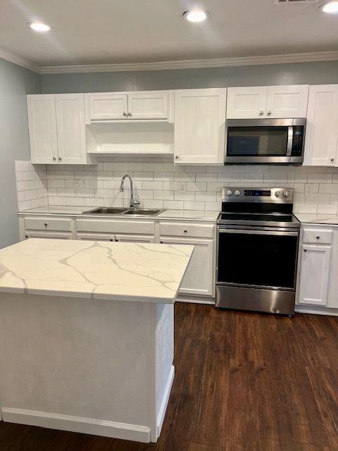 kitchen featuring light stone counters, appliances with stainless steel finishes, sink, and white cabinets