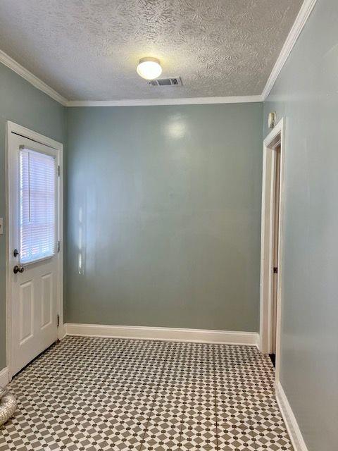 entryway with crown molding and a textured ceiling