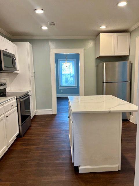 kitchen with appliances with stainless steel finishes, a kitchen island, and white cabinets