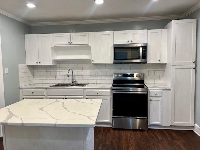 kitchen with light stone counters, stainless steel appliances, sink, and white cabinets