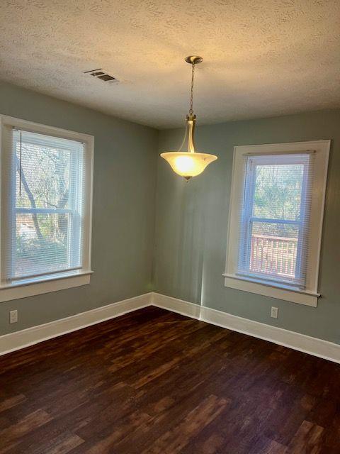 unfurnished dining area with dark hardwood / wood-style floors and a textured ceiling