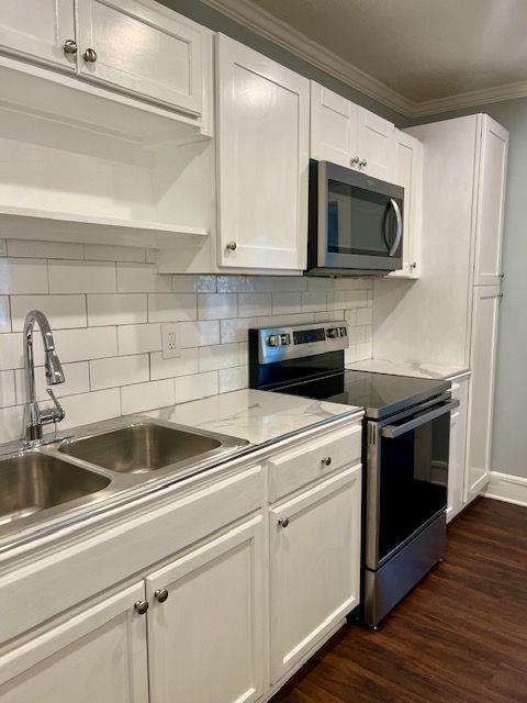 kitchen with backsplash, stainless steel appliances, sink, and white cabinets