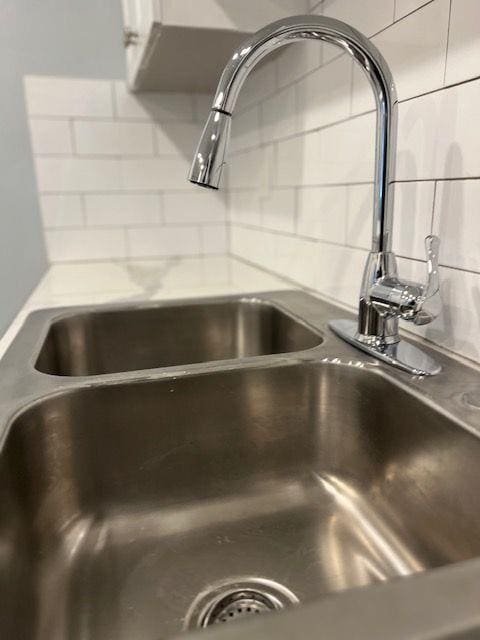 interior details with light stone counters, sink, and decorative backsplash