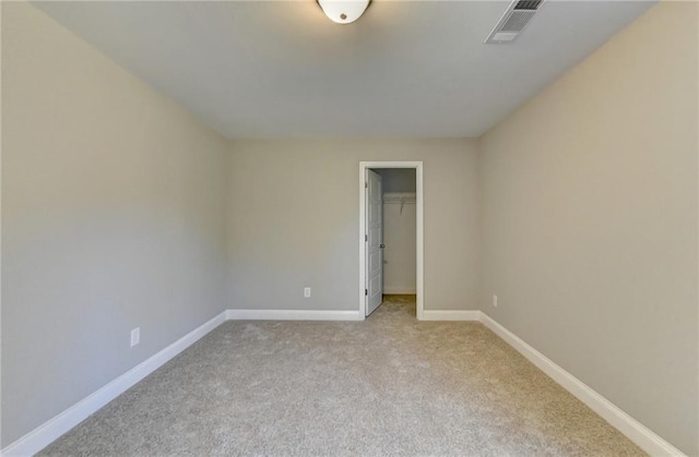 unfurnished bedroom with light colored carpet, a closet, and a walk in closet