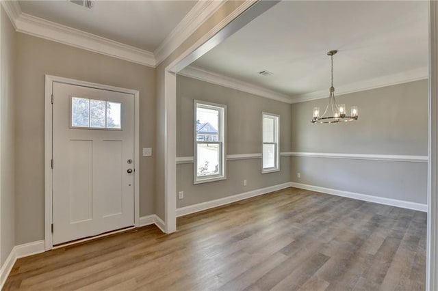 foyer featuring ornamental molding, hardwood / wood-style flooring, and a chandelier