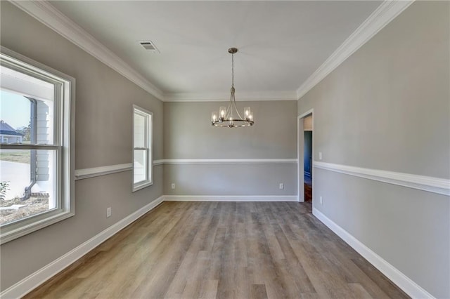 unfurnished dining area featuring ornamental molding, hardwood / wood-style flooring, and a chandelier