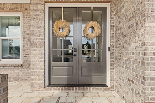 property entrance featuring french doors and brick siding