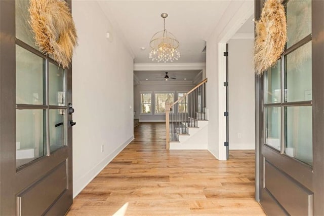 foyer with baseboards, an inviting chandelier, stairs, crown molding, and light wood-type flooring