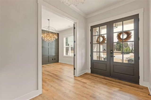 doorway featuring french doors, light wood finished floors, ornamental molding, a chandelier, and baseboards