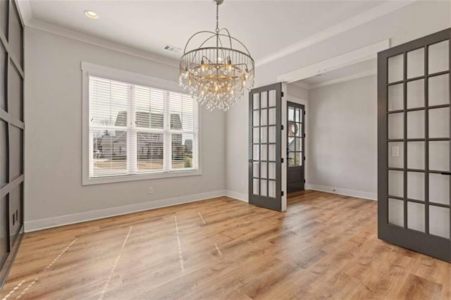 unfurnished dining area with wood finished floors, baseboards, ornamental molding, french doors, and an inviting chandelier