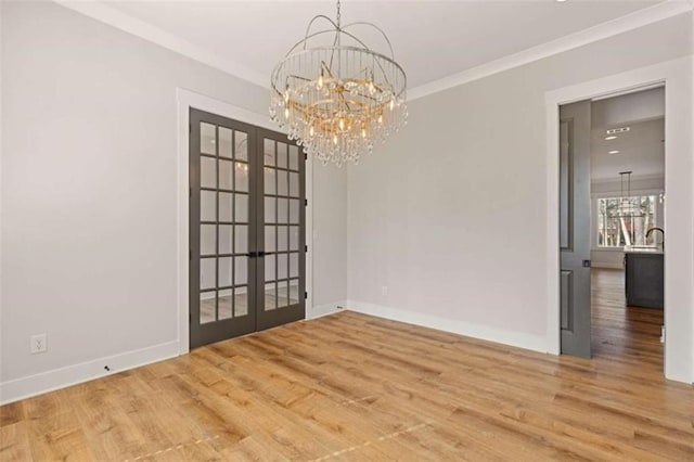 spare room featuring french doors, a notable chandelier, baseboards, and wood finished floors