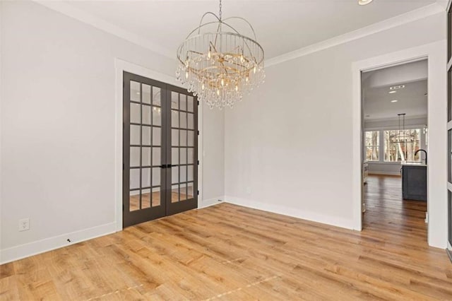 empty room featuring french doors, a notable chandelier, and wood finished floors