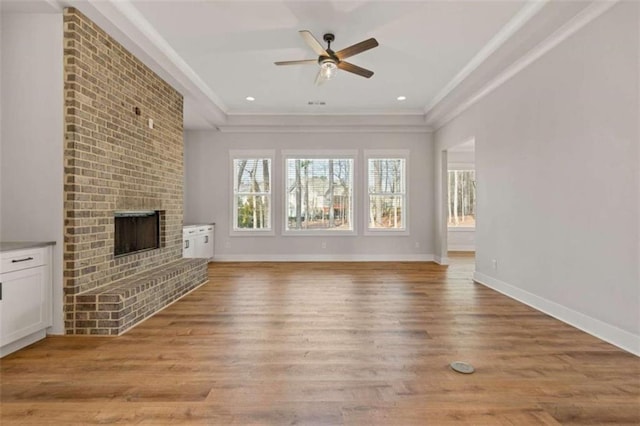 unfurnished living room with light wood finished floors, a fireplace, baseboards, and crown molding