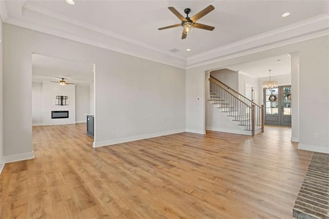 unfurnished living room with light wood-type flooring, a large fireplace, stairs, and baseboards