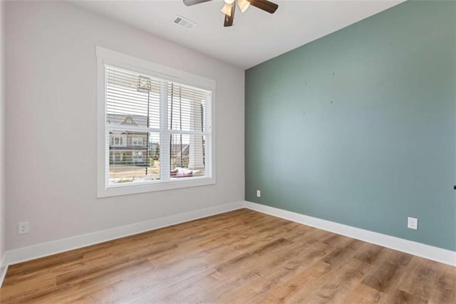 empty room with a ceiling fan, wood finished floors, visible vents, and baseboards