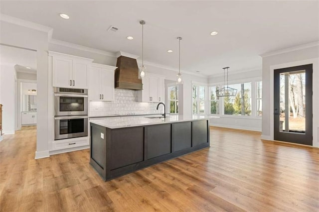 kitchen with double oven, white cabinets, light countertops, backsplash, and custom exhaust hood