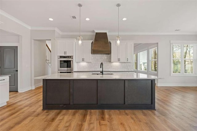 kitchen with a sink, white cabinets, light countertops, custom exhaust hood, and tasteful backsplash