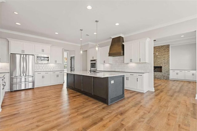 kitchen with premium range hood, white cabinetry, light countertops, appliances with stainless steel finishes, and light wood finished floors