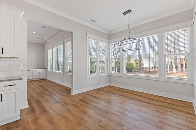 unfurnished dining area with ornamental molding, light wood-style flooring, and baseboards