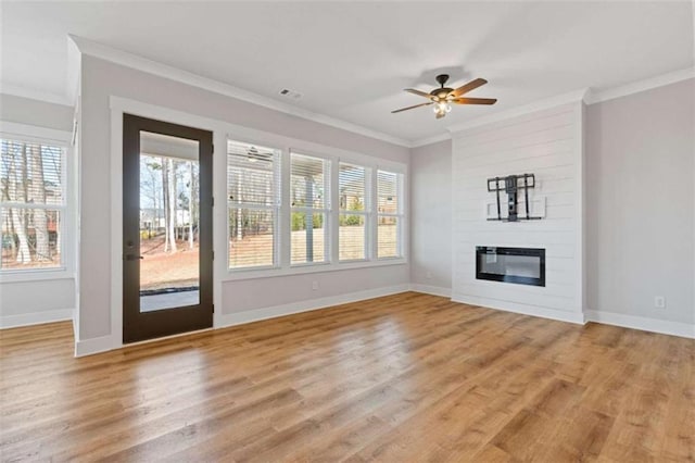 unfurnished living room featuring light wood-type flooring, ornamental molding, a fireplace, and baseboards