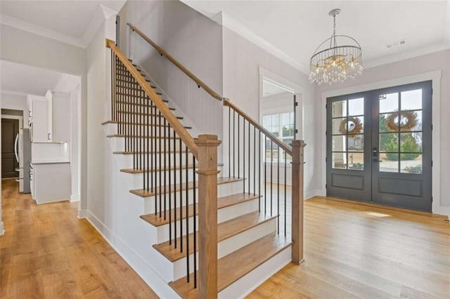 entryway with light wood-style floors, a healthy amount of sunlight, visible vents, and ornamental molding