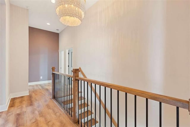 hall with a chandelier, recessed lighting, wood finished floors, an upstairs landing, and baseboards