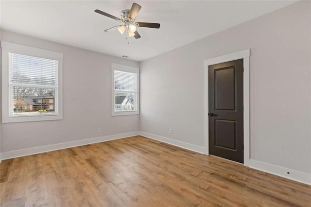 spare room with ceiling fan, baseboards, and light wood-style flooring