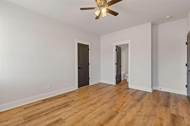 unfurnished bedroom featuring light wood-type flooring, connected bathroom, a ceiling fan, and baseboards